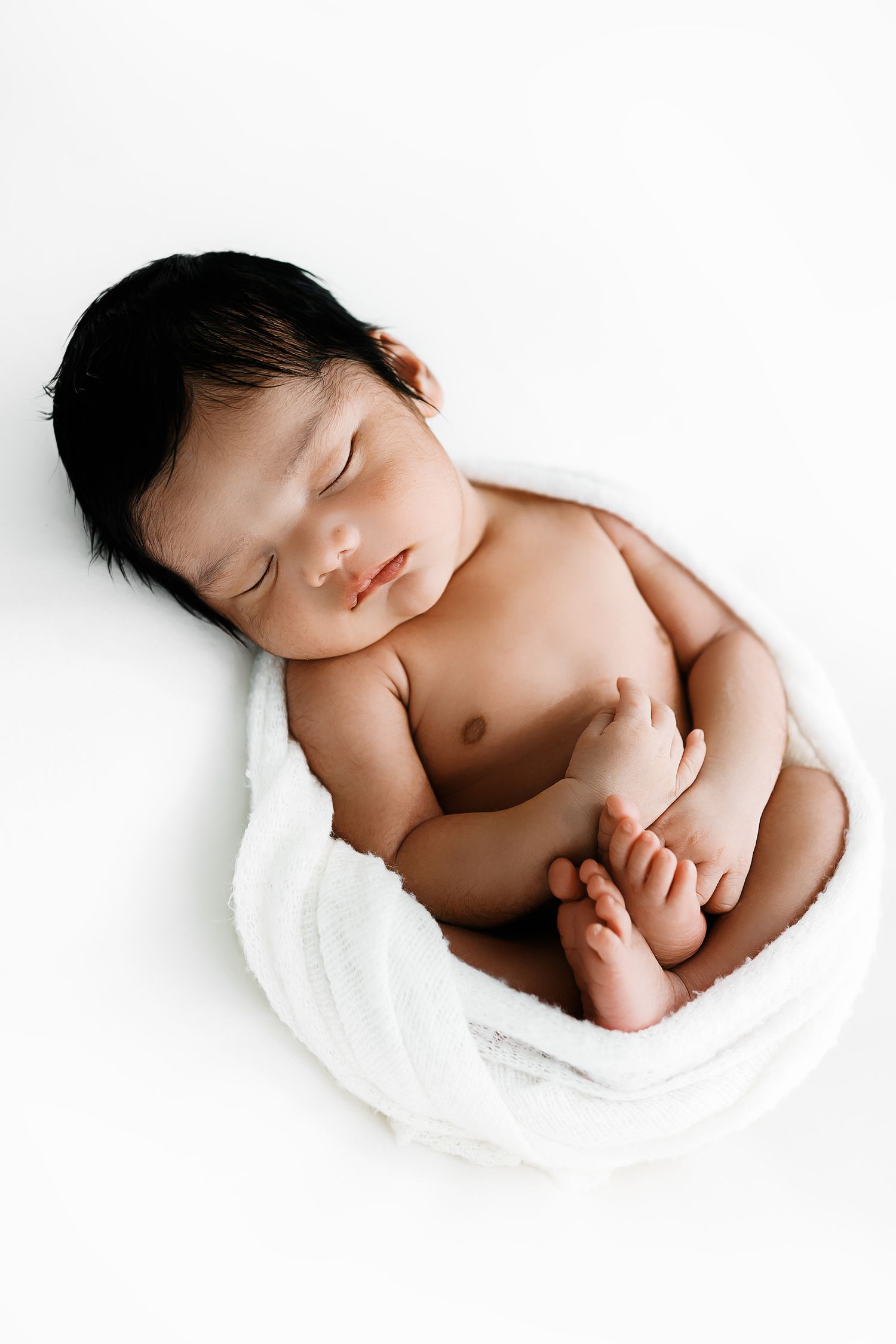 A peaceful newborn baby sleeps swaddled in soft white fabric in a collection of three artistic photos.