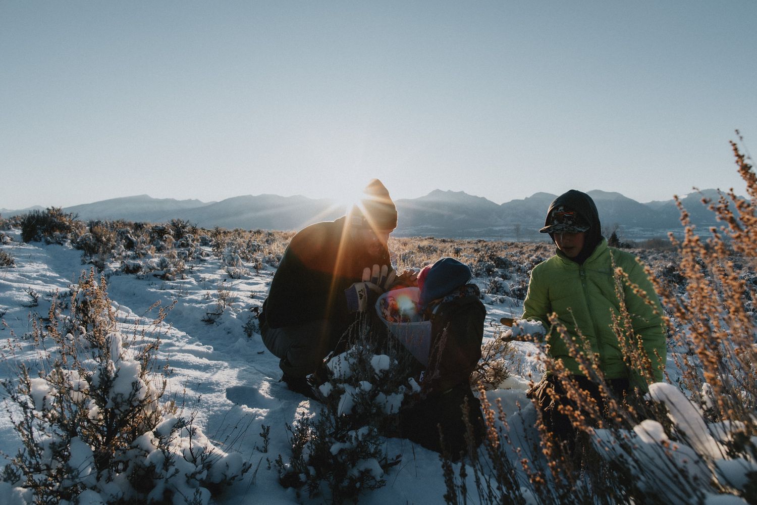 A dad adjusting his baby in their osprey carrier, during a winter hike in the Bitterroot.