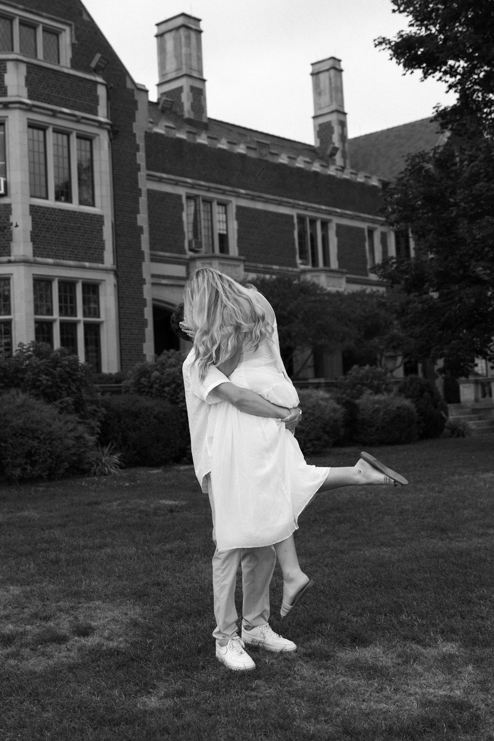 A romantic lift pose captured in black and white against a historic building backdrop.
