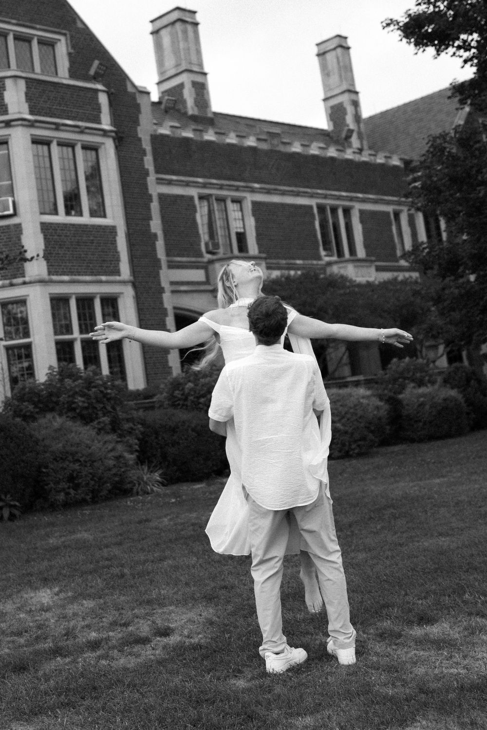 A romantic pose with arms spread wide against historic architecture in black and white.