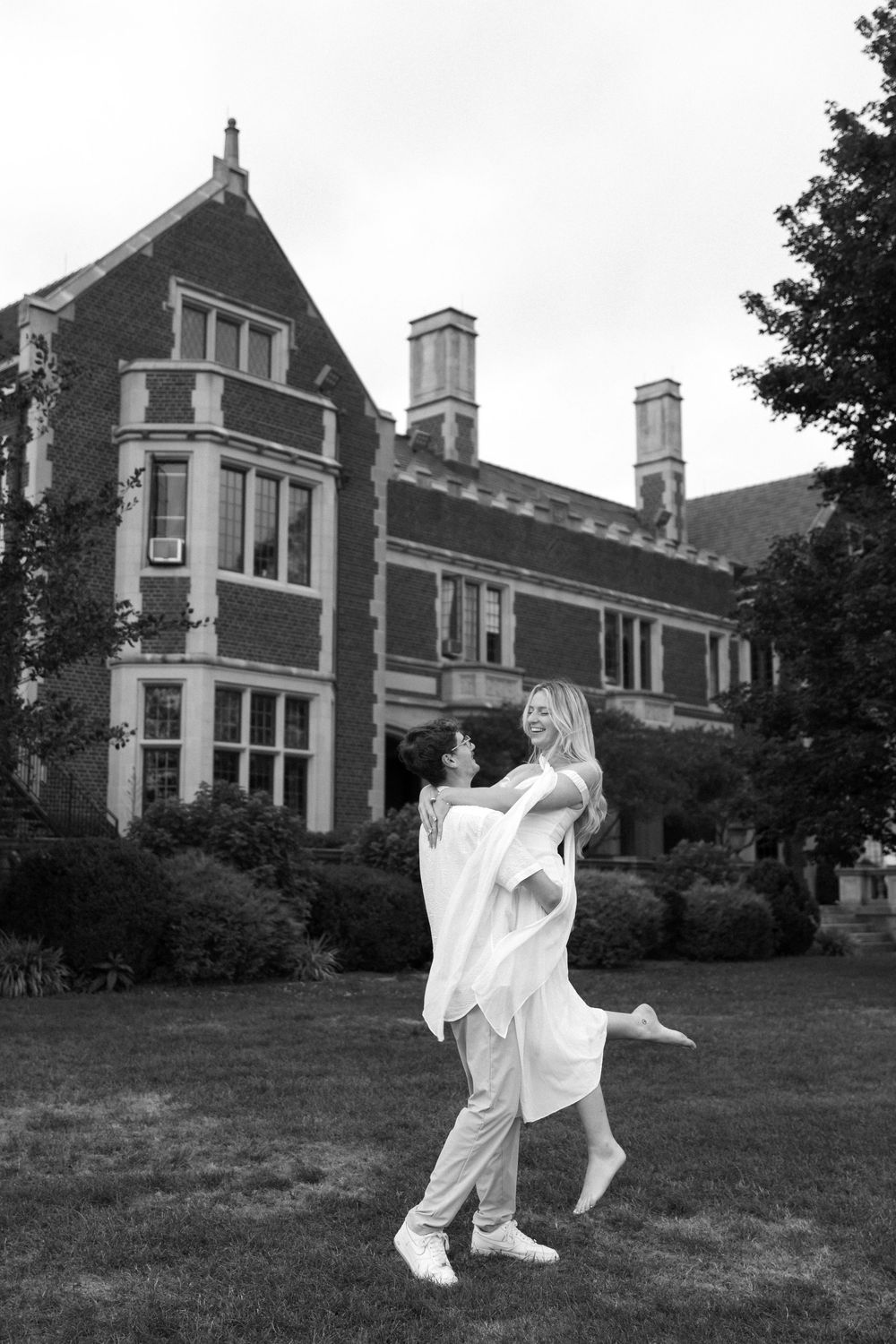 A joyful lift pose captured in black and white against classic architecture.