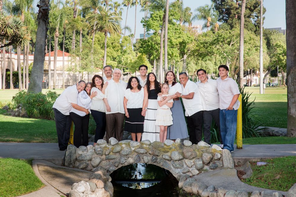 A group photo taken outdoors with palm trees and stone features in the background.