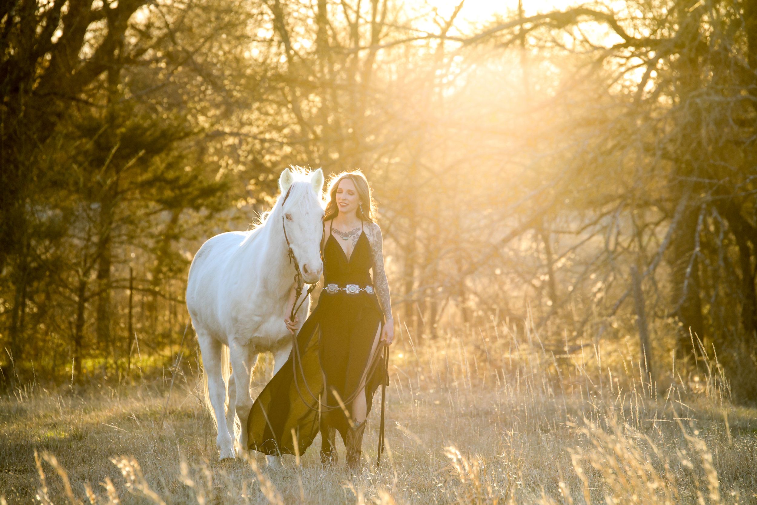 girl wearing black dress walking next to white horse at golden hour sunset, equestrian portraits, horse photographer