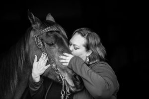 black and white image of a woman hugging her horse