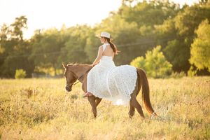 woman in wedding dress riding horse