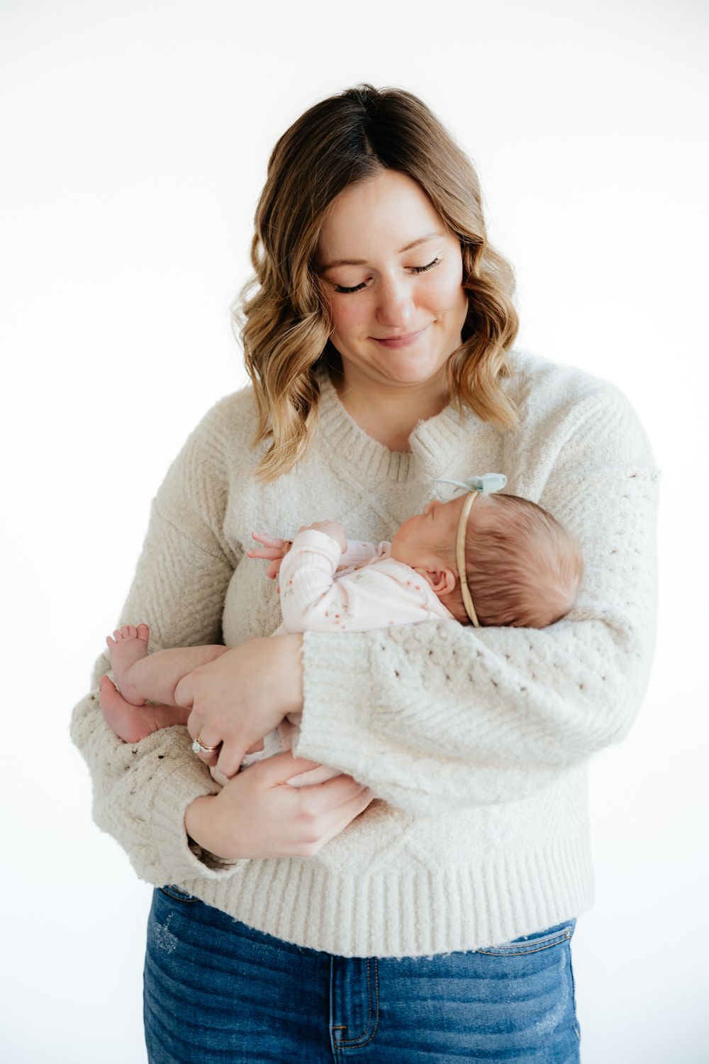 A tender moment captured in white as a parent cradles a newborn baby against a soft sweater.