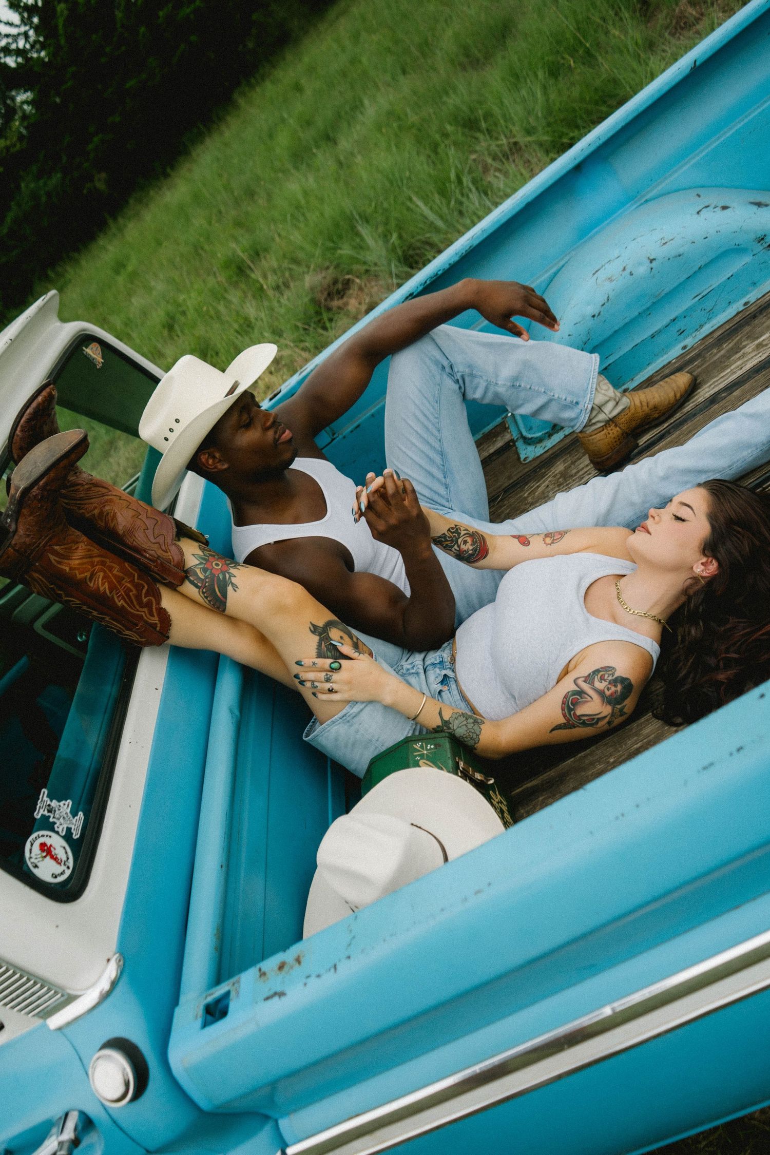 A couple relaxes together in a bright blue boat on a sunny afternoon.