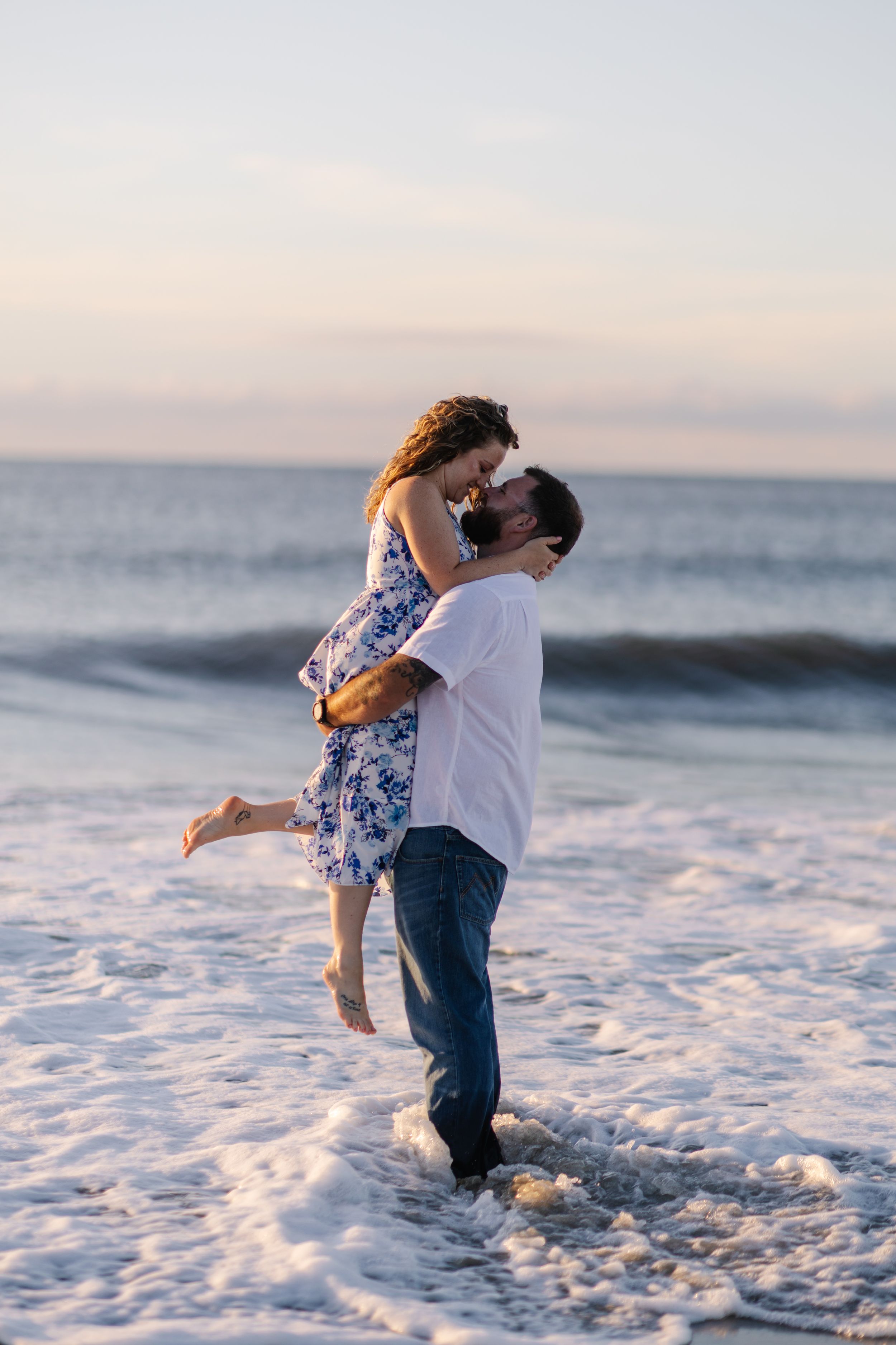A couple embraces in the ocean waves at sunset, creating a series of romantic silhouettes on the beach.