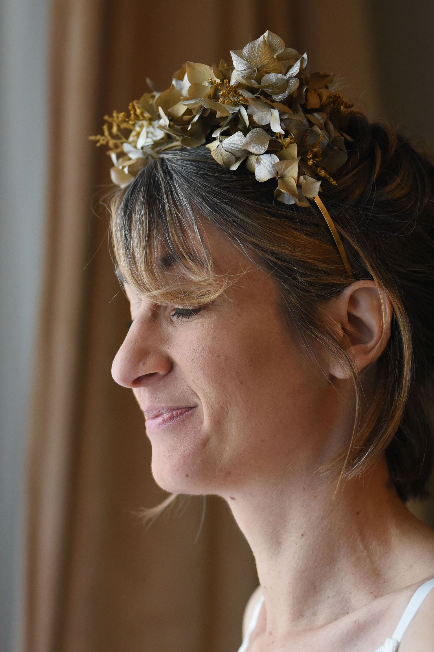 Portrait wearing delicate white floral crown against dark background.