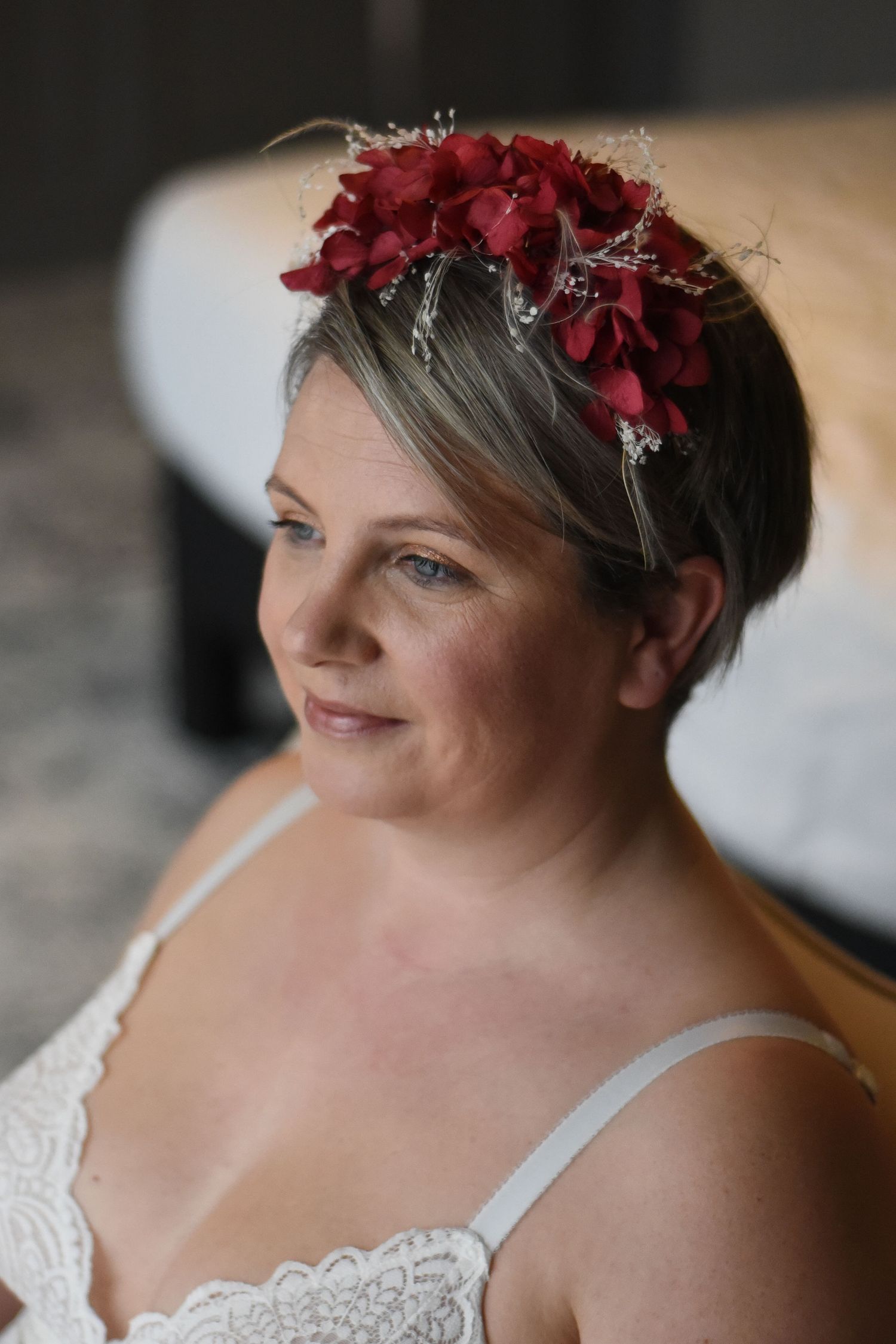 Elegant portrait with deep red floral headpiece and white lace straps.
