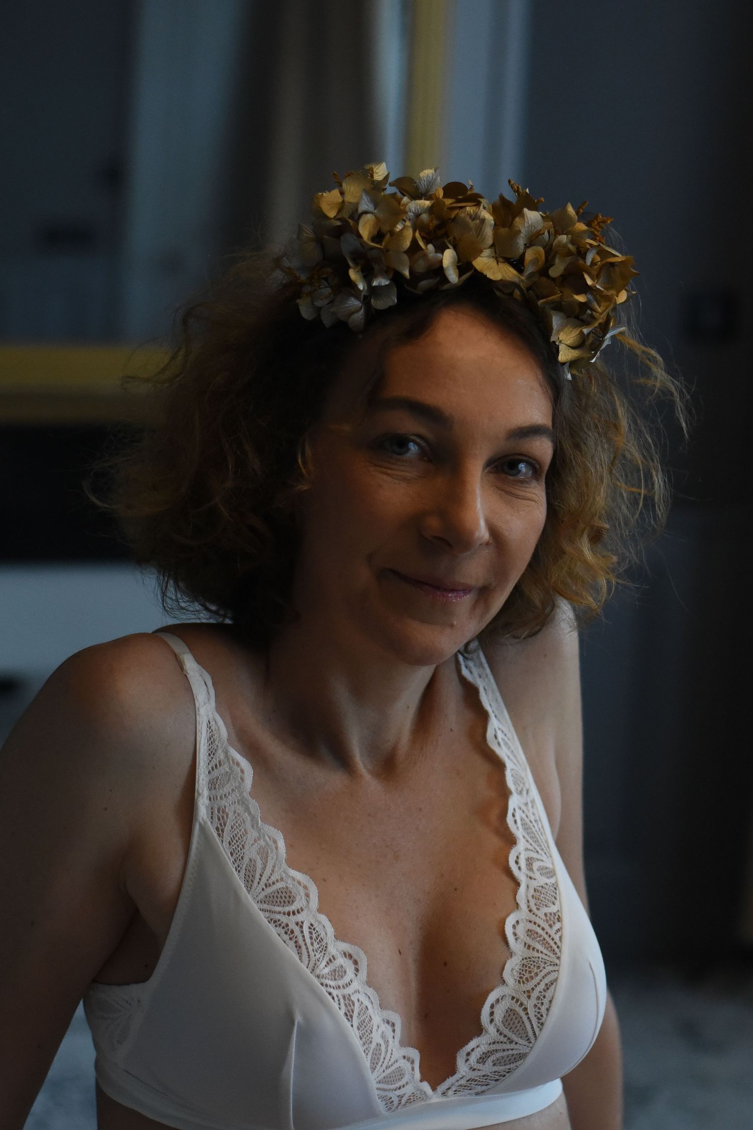 A romantic portrait series showing someone wearing a white lace top and golden leaf crown in soft lighting.