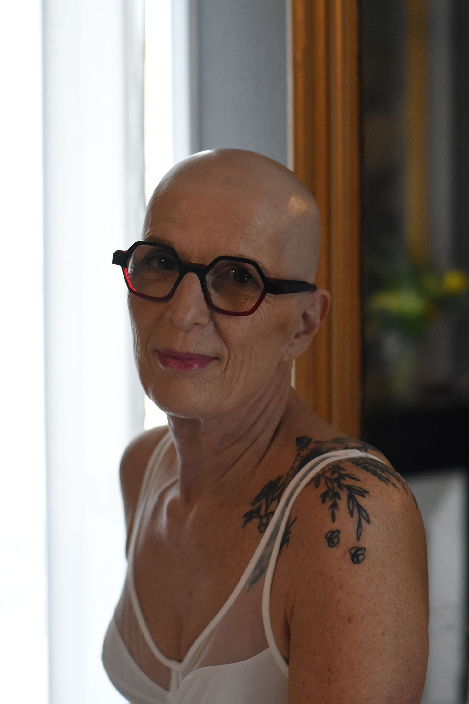 A series of expressive portraits showing someone in glasses and a white top with a floral shoulder tattoo.