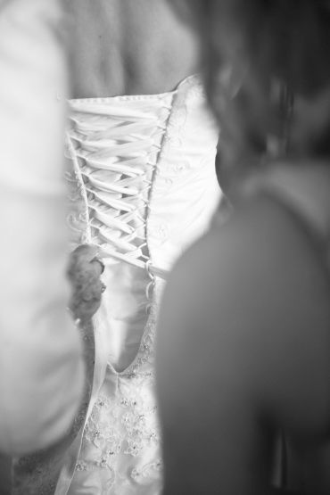 Reportage detail shot of wedding dress being laced up