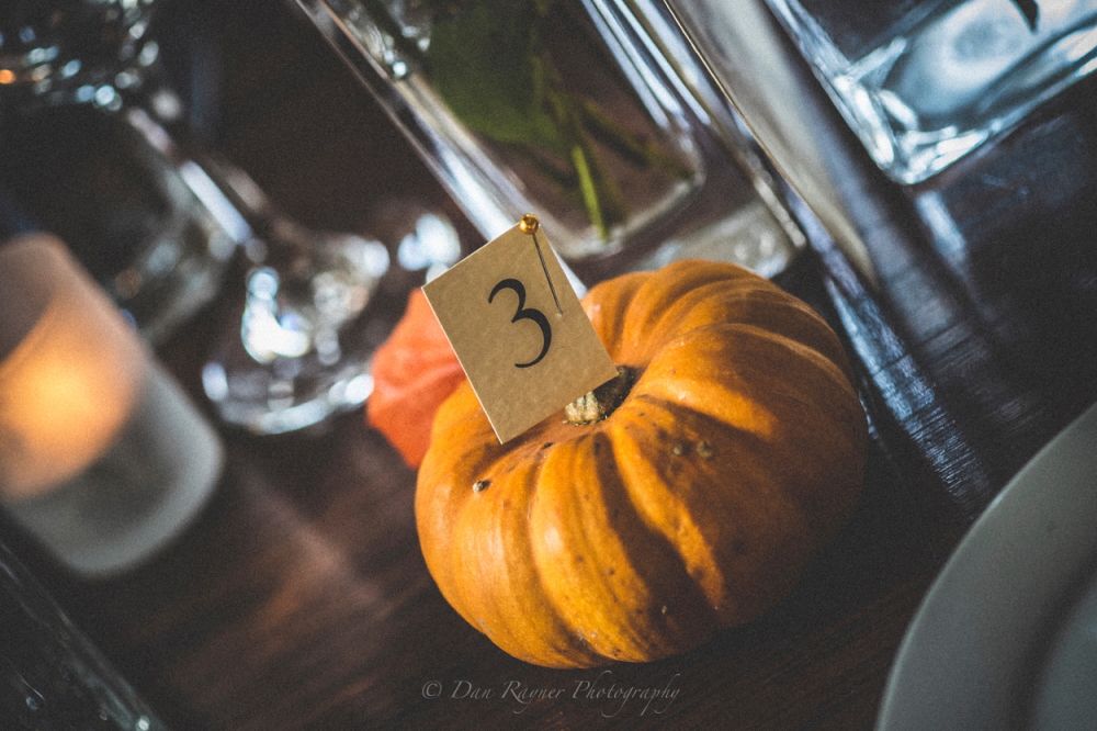 Reportage detail shot of October wedding breakfast table number pumpkin