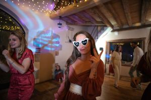 Dance floor filled with party guests under twinkling string lights.