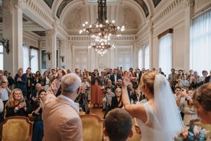 Bride walking down the aisle in an elegant ballroom filled with wedding guests during a ceremony.