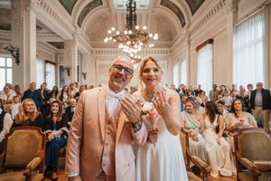 Newlyweds showing wedding rings at elegant ceremony venue.