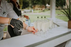 A row of champagne glasses being set up at an outdoor wedding reception.