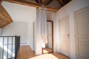 Interior of rustic room with exposed wooden beams and white painted walls.