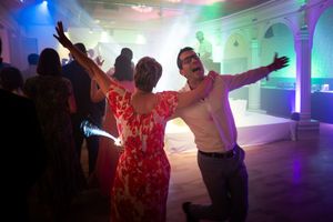 Couple dancing energetically on a colorful illuminated wedding reception dance floor.