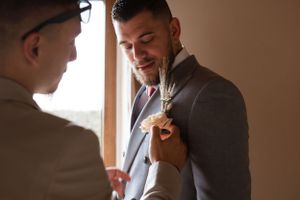 A light gray suit jacket with a peach-colored rose boutonniere in the lapel.