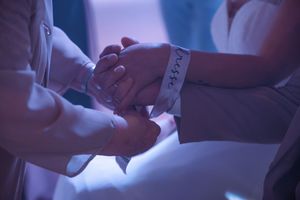 Couple holding hands during wedding ceremony with bracelet detail.