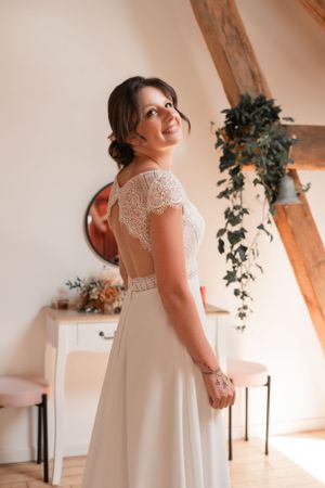 Elegant white wedding dress with delicate lace details and cap sleeves.