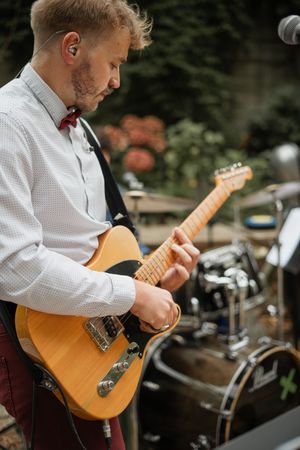 Male musician playing a Telecaster electric guitar at an outdoor wedding reception performance.