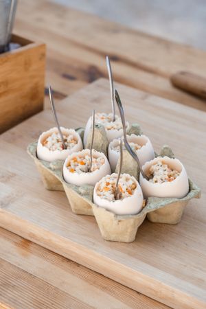 Small appetizers served in individual pastry cups on a wooden surface.