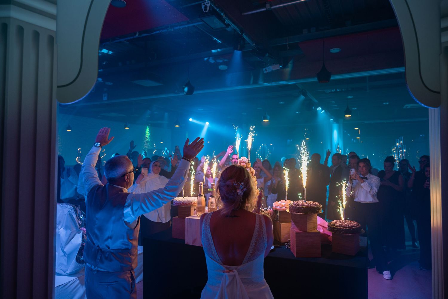 Bride and groom celebrating at wedding reception with sparklers.