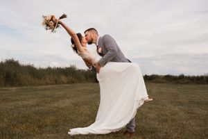 Couple dancing and embracing in an outdoor field during their wedding celebration.