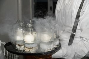 Dramatic display of smoking cocktails on a dark surface with atmospheric lighting.
