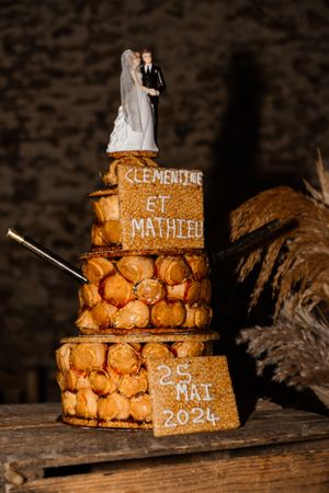 French croquembouche wedding cake decorated with caramel and names displayed on wooden surface.