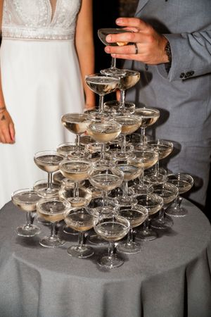 Elegant champagne tower with coupe glasses arranged on gray tablecloth.