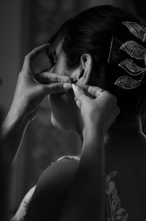 Close-up black and white shot of someone adjusting jewelry or hair accessories.
