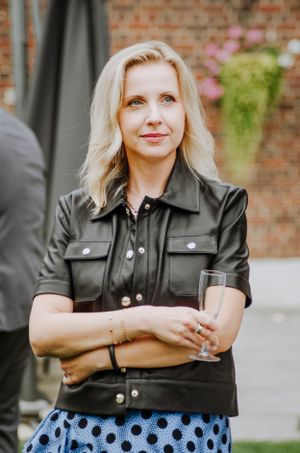 Person in black leather jacket and polka dot skirt posing outdoors.