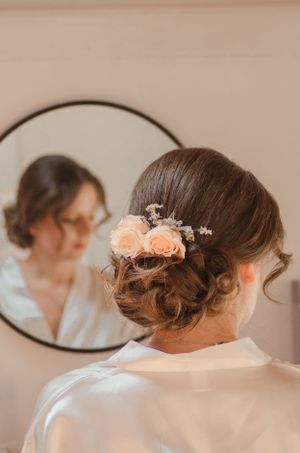 Elegant bridal updo hairstyle decorated with peach flowers and delicate baby's breath.
