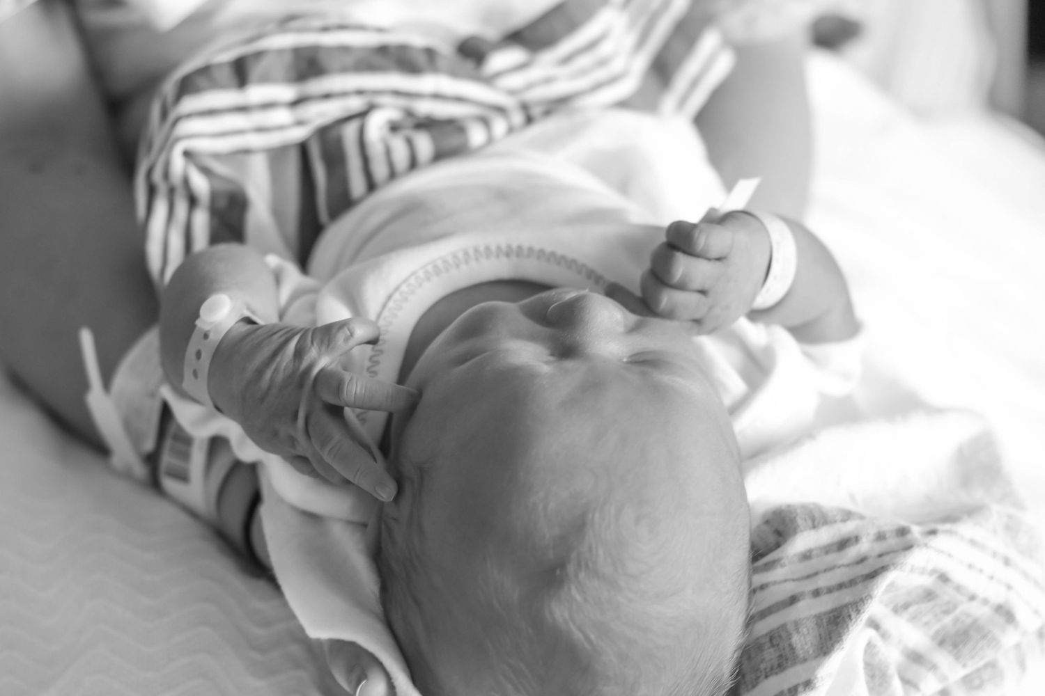 Black and white image of a sleeping newborn in striped clothing.