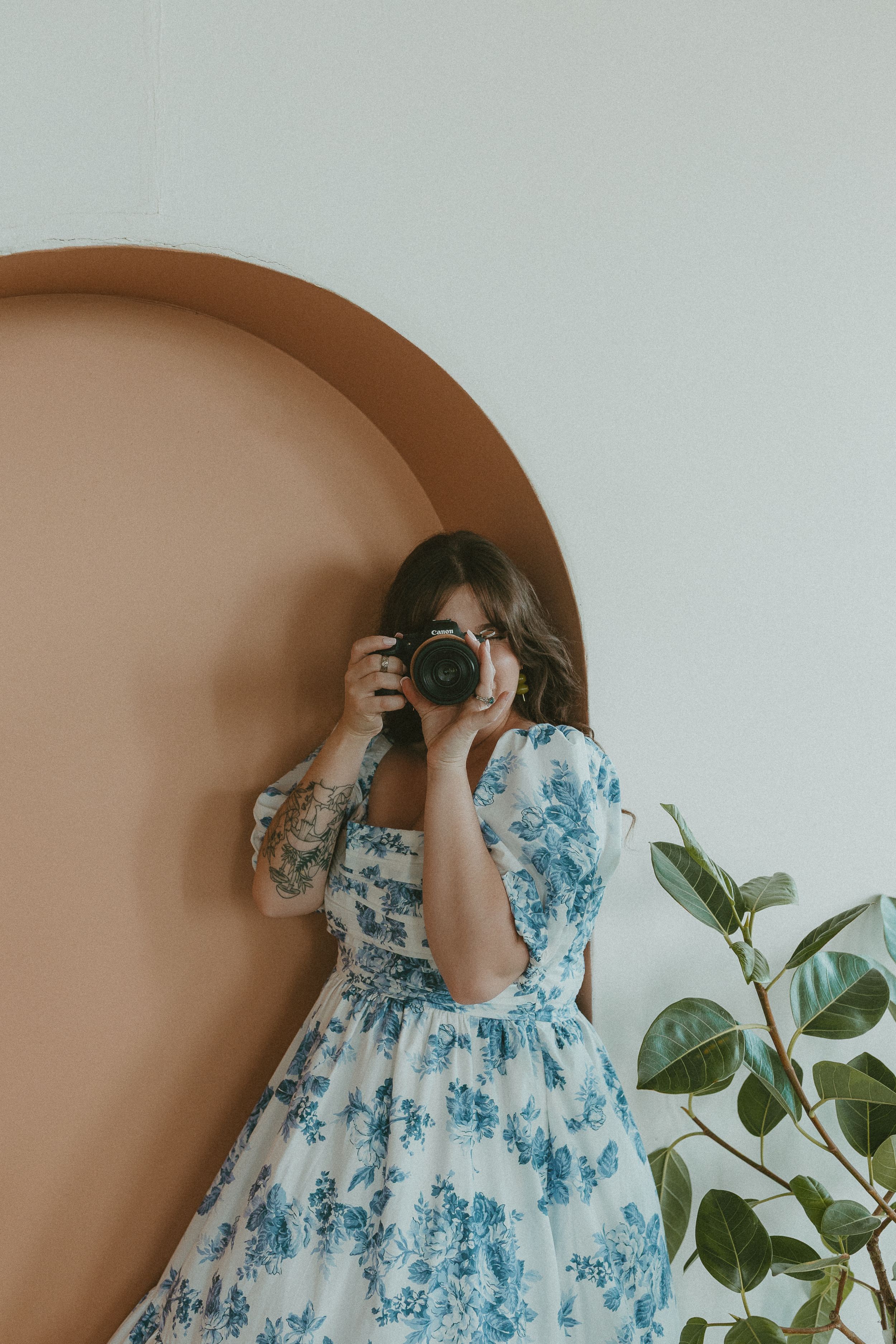 A sequence of progressive shots showing someone using a vintage camera against a cream-colored wall with a houseplant.