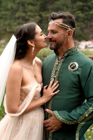 A romantic wedding couple sharing an intimate moment, with the groom wearing a decorated green ceremonial outfit.