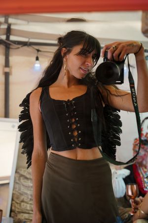 Person wearing a black corset top with feather details and lace-up design.