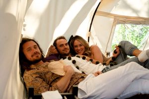 People relax together inside a white tent during an outdoor celebration.