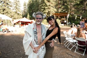 Guests mingling and laughing at outdoor wedding reception with white chairs.