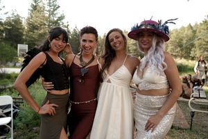 Wedding party members celebrating together in an outdoor forest setting.