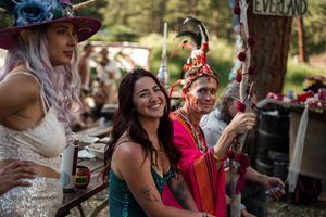 A festive outdoor celebration with people in colorful outfits enjoying drinks and laughter at a summer gathering.