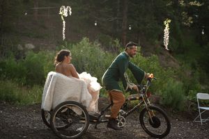 A unique wedding transport featuring a decorated bicycle pulling a sidecar through a wooded forest setting.