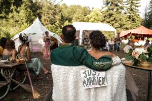 Attendees wrapped in blankets watch festivities at an outdoor celebration with white tents in the background.