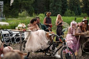 Wedding guests celebrating around bicycles at an outdoor forest reception.