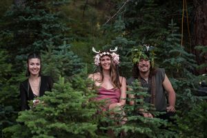 Friends gather in a forested setting during an outdoor celebration.