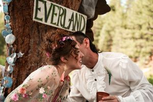 A rustic woodland wedding ceremony with decorative signs and floral arrangements.
